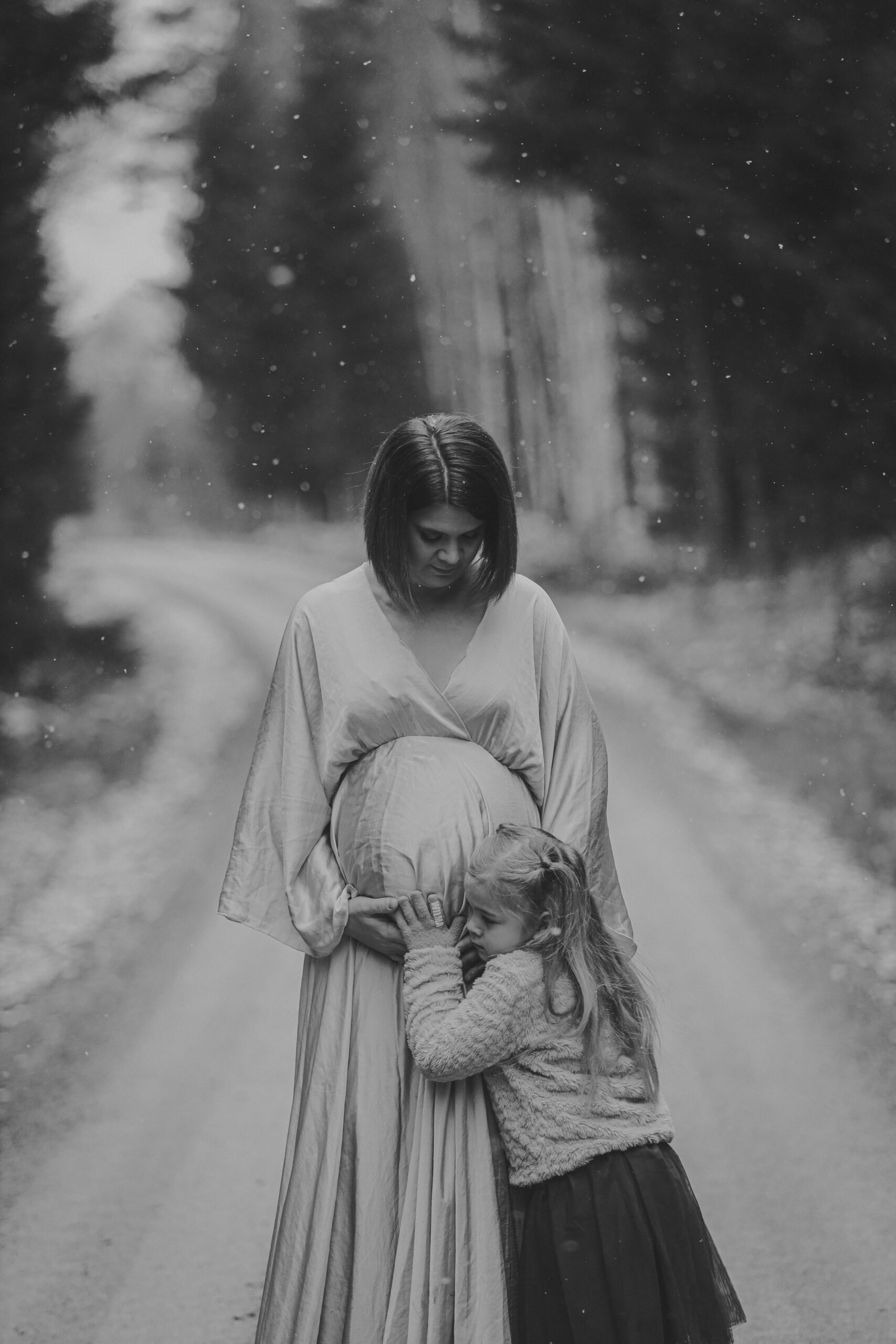 Gravidbild på kvinna i snö på skogsväg