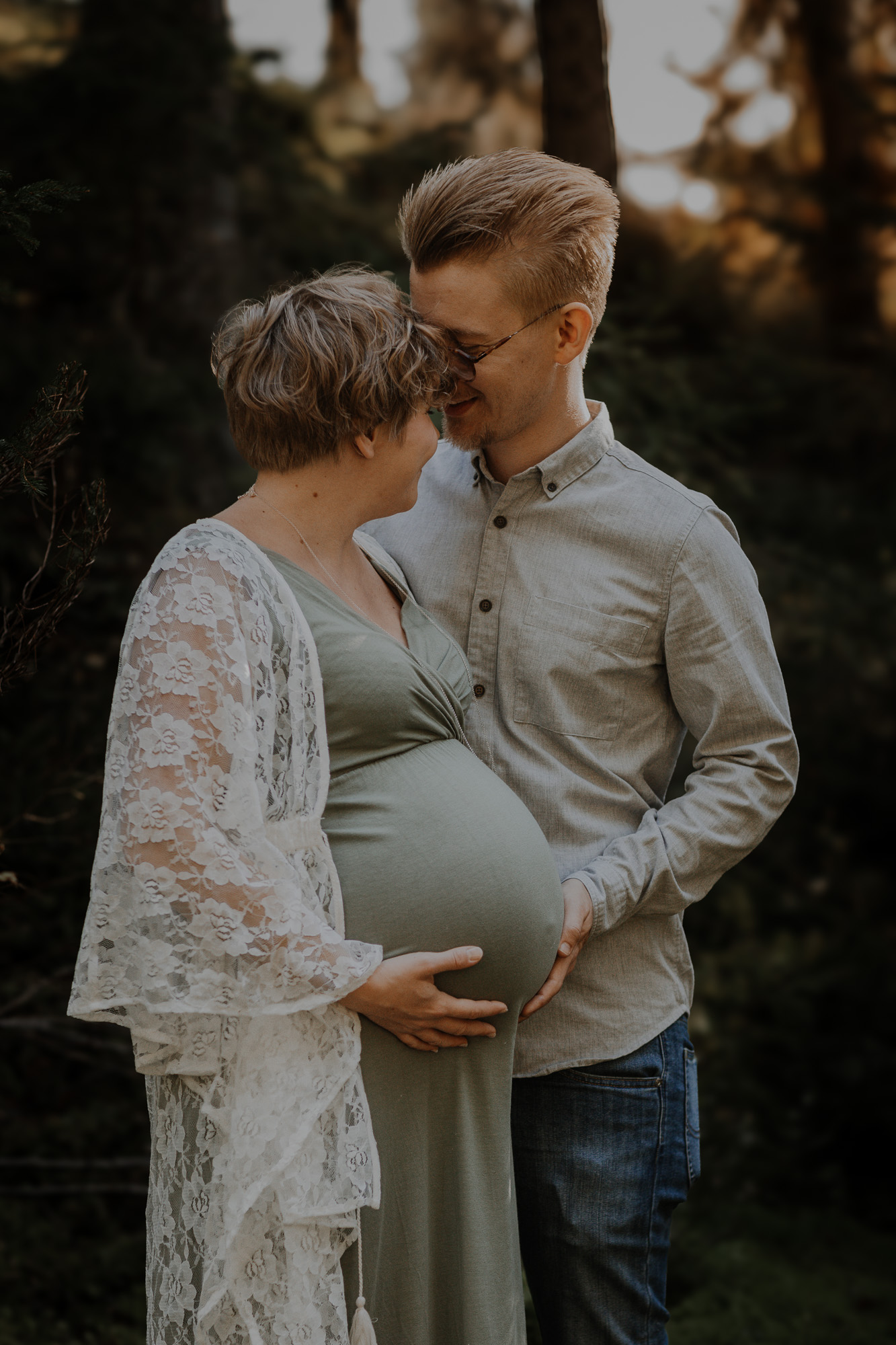 Gravidfoto med blivande föräldrar i skogsmiljö